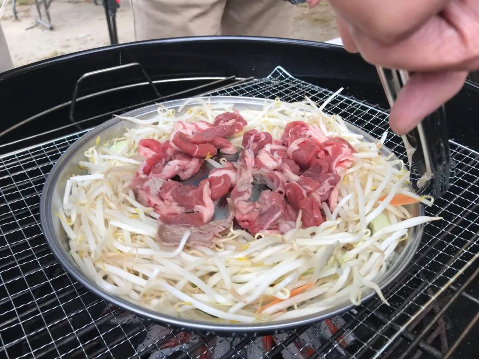鍋に肉と野菜をのせる調理中の手元